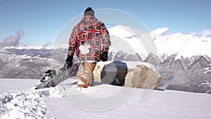 Snowboarder walks high in the mountains on deep snow with snowboard