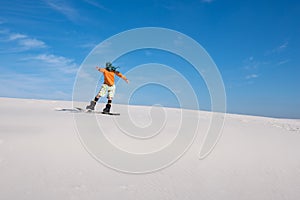 Snowboarder, wearing a scarf rides on sand dune