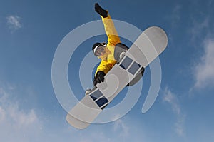 Snowboarder In Winter Clothes Jumping Against Sky