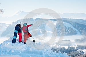 Snowboarders couple standing on top of the mountain