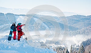 Snowboarders couple standing on top of the mountain