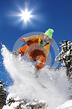 Snowboarders jumping against sun