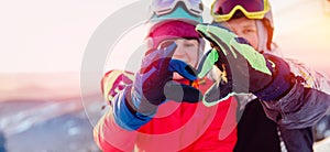 Snowboarders man and woman show heart sign with hands, winter travel love banner concept