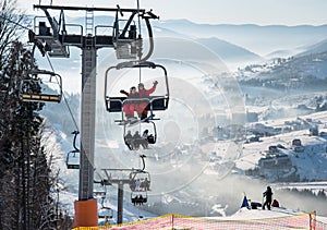 Snowboarders and skiers on a ski lift at winter ski resort