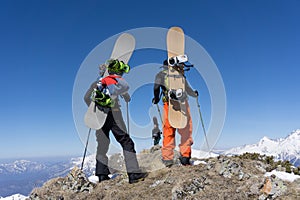 Snowboarders standing on top of a mountain