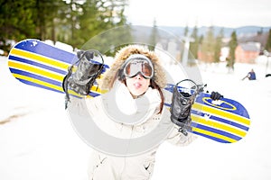 Snowboarding.Young beautiful woman with ski mask holding her snowboard at ski slope Young woman in ski resort