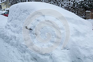 Snowbound car in the street, buried under a big snow layer