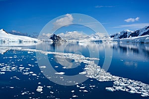 Snowcapped mountains in beautiful landscape, reflecting in blue water, ice flows, Lemaire Channel near Paradise Bay, Antarctica