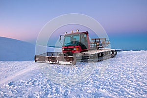 Snowcat on a mountain at sunrise on a frosty morning in winter.