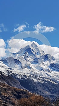 Snowcovered mountain under a blue sky with fluffy clouds on the horizon