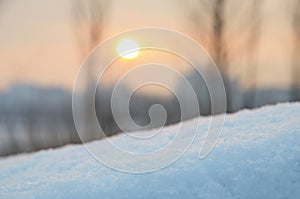 Snowdrift against sky and sun over buildings at sunset.