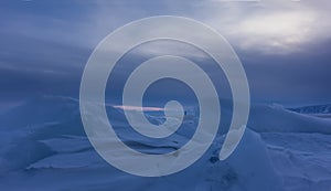 Snowdrifts and ice floes against the background of the evening cloudy sky