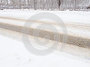 Snowdrifts on the side of the road. Bad weather and traffic. Snow on asphalt. Difficult driving conditions. Winter slosh