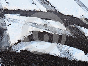Snowdrifts on the side of the road. Bad weather and traffic. Snow on asphalt. Difficult driving conditions. Winter slosh