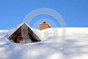 Snowed roof window of an old wooden house