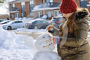 Snowfall a funny girl in a sculpts a snowman in the park