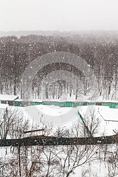 Snowfall over woods and car garages in winter