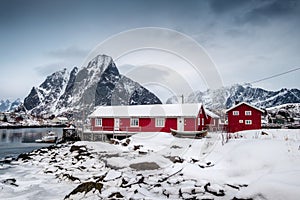 Snowfall on red house with harbor in valley on arctic ocean