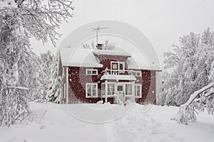 Snowfall in the village. Blurred background. Old wooden house in the snow. Traditional typical Scandinavian Swedish house or villa