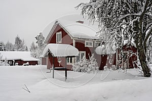 Snowfall in the village. Blurred background. Old wooden house in the snow. Traditional typical Scandinavian Swedish house or villa