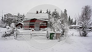 Snowfall in the village. Blurred background. Old wooden house in the snow. Traditional typical Scandinavian Swedish house or villa