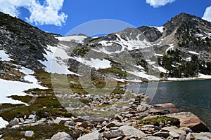Snowfields, Mountain Peaks, and Rocks Surrounding a High Mountain Lake photo