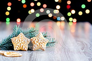 Snowflake cookies next to the spruce twigs on a blurry background with bokeh.