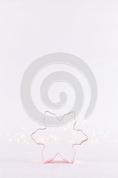 Snowflake Copper cookie cutter on white sparkling background with bokeh lights. Holiday Christmas and New Year