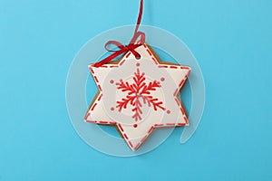 Snowflake shaped Christmas cookie on light blue background, top view