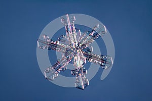 Snowflake on smooth gradient background. Macro photo of real snow crystal on glass surface. This is small snowflake with