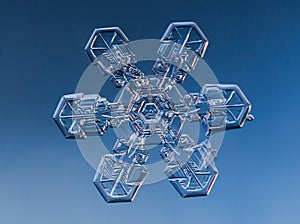 Snowflake on smooth gradient background. Macro photo of real snow crystal on glass surface. This is small snowflake with