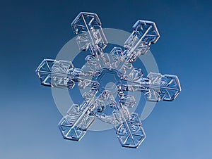 Snowflake on smooth gradient background. Macro photo of real snow crystal on glass surface. This is small snowflake with