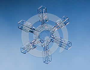 Snowflake on smooth gradient background. Macro photo of real snow crystal on glass surface. This is small snowflake with