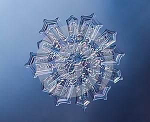 Snowflake on smooth gradient background. Macro photo of real snow crystal on glass surface. This is small snowflake with