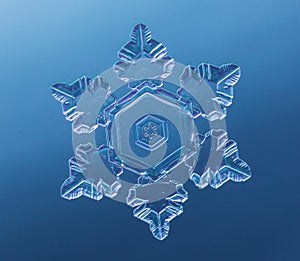 Snowflake on smooth gradient background. Macro photo of real snow crystal on glass surface. This is small snowflake with