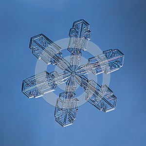 Snowflake on smooth gradient background. Macro photo of real snow crystal on glass surface. This is small snowflake with