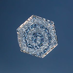 Snowflake on smooth gradient background. Macro photo of real snow crystal on glass surface. This is small snowflake with