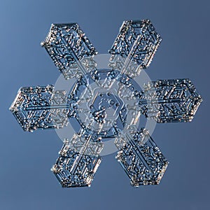 Snowflake on smooth gradient background. Macro photo of real snow crystal on glass surface. This is small snowflake with