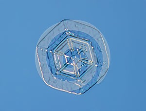 Snowflake on smooth gradient background. Macro photo of real snow crystal on glass surface. This is small snowflake