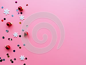 Snowflakes, confetti and red Christmas balls on a pink background, flatly, copyspace. Bright Christmas holiday concept. New year`