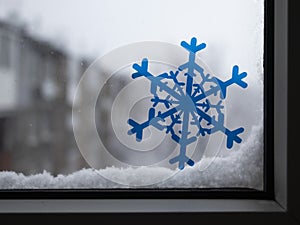 Snowflakes on the glass window on the background of the snow-covered city.