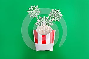 Snowflakes in a white and red french fries paper box on blue background. Christmas and New year concept. Front view