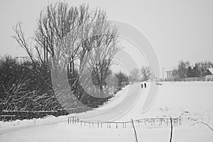 Snowing landscape in the park with people passing by