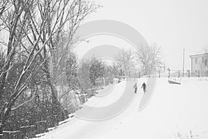 Snowing landscape in the park with people passing by