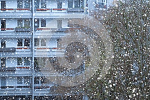 snowing outside against backdrop of multi-story building, urban landscape, winter weather conditions and snowfall, video shooting