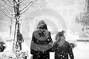 Snowing urban landscape with people passing by