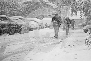 Snowing urban landscape with people passing by photo