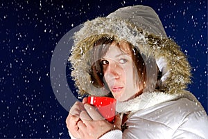 Snowing on young woman drinking something hot