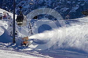 snowmaking cannon sprays snow on the ski slope