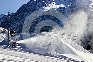 snowmaking cannon sprays snow on the ski slope